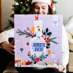Aroma Olymp – Frau mit Weihnachtsmütze hält den Bio Feinkost Adventskalender Vegan 2025 Aromatic Advent.