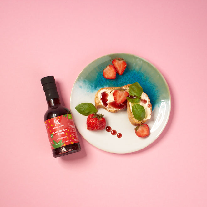 
                  
                    Aroma Olymp Bio Balsamico Creme mit Erdbeeren. Präsentiert neben einem Teller mit Baguette, Erdbeeren und Balsamico als Serviervorschlag.
                  
                