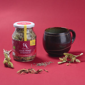 
                  
                    Aroma Olymp Bio Kräuterteemischung "Greek Winter". Präsentiert auf rotem Grund, daneben eine Tasse mit Tee und Kräuter.
                  
                